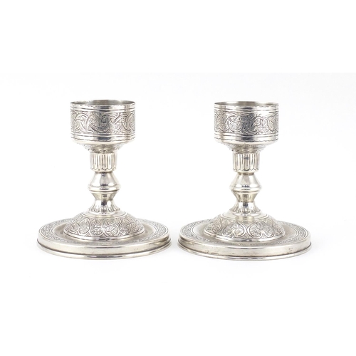 887 - Pair of Persian silver candlesticks with engraved decoration, impressed marks to the base, 11cm high... 