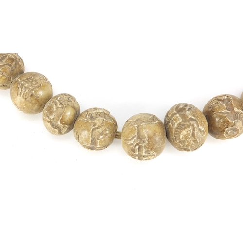 709 - Islamic stone bead necklace, each bead carved with mythical animals, each approximately 3cm in diame... 