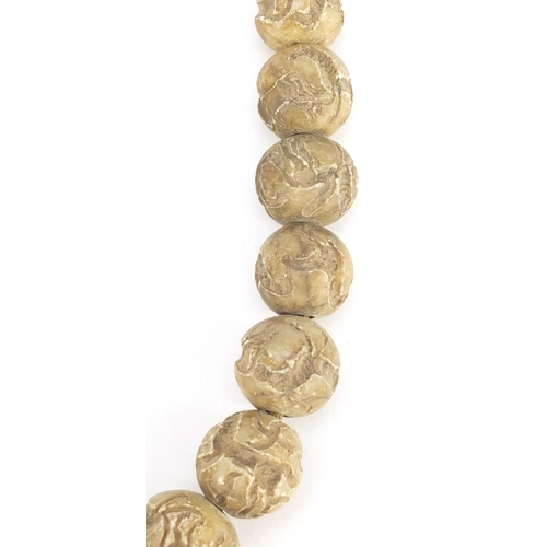 709 - Islamic stone bead necklace, each bead carved with mythical animals, each approximately 3cm in diame... 