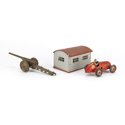 353 - German tin plate garage with clock work racing car and a Marx Toys field gun