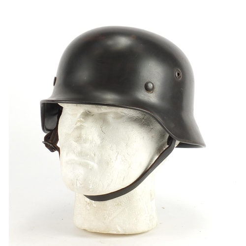 309 - German Military interest tin helmet with decal and leather liner, impressed marks to the interior