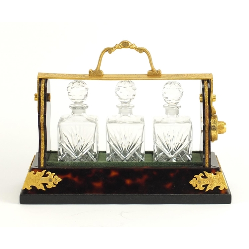 2193 - Boulle style three bottle tantalus with gilt metal mounts, housing three cut glass bottles, 26.5cm w... 