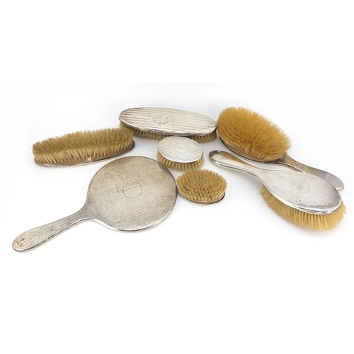 2670 - Six silver backed vanity brushes and a hand mirror, various hallmarks, the largest 29cm in length