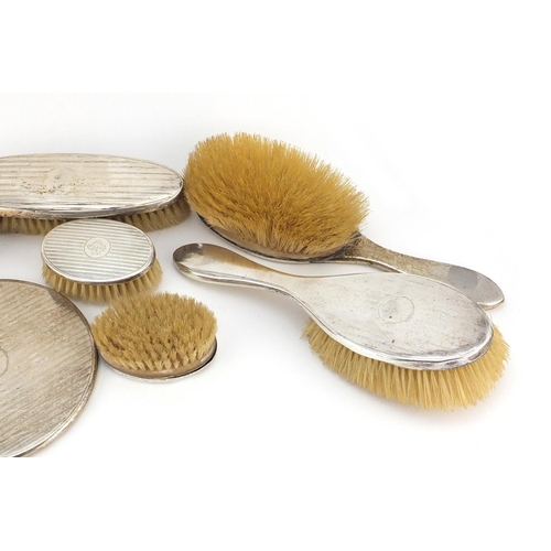 2670 - Six silver backed vanity brushes and a hand mirror, various hallmarks, the largest 29cm in length