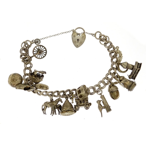 2824 - Silver charm bracelet with selection of mostly silver charms including a cow bell, windmill, woodpec... 