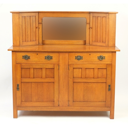 2076 - Arts & Crafts oak side cabinet with mirrored back, flanked by two cupboard doors above two drawers a... 
