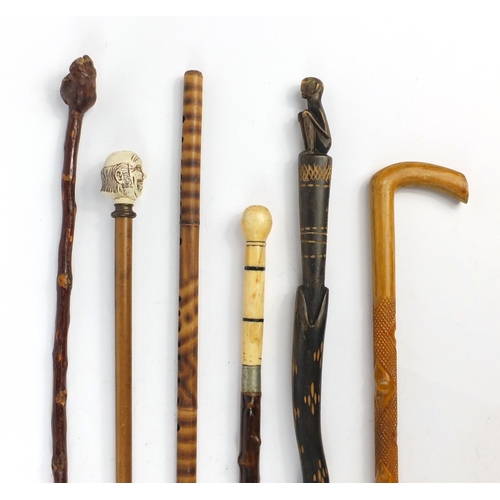 631 - Six wooden walking sticks including one with ivory handle and an African figure, the largest 115cm i... 