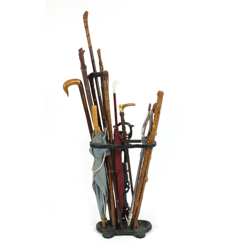 96 - Victorian style cast iron stick stand with a selection of walking sticks, a horn handled riding crop... 