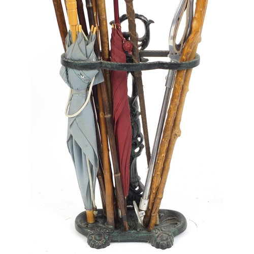 96 - Victorian style cast iron stick stand with a selection of walking sticks, a horn handled riding crop... 