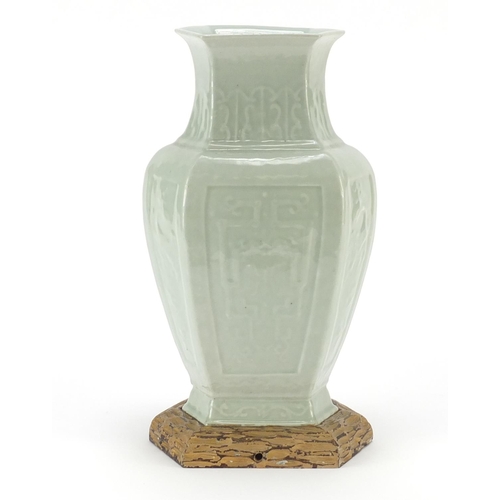 2323 - Chinese hexagonal celadon glazed vase raised on hardwood stand, decorated in low relief with panels ... 