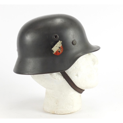 2463 - German Military interest tin helmet with decals and leather liner, impressed marks to the interior