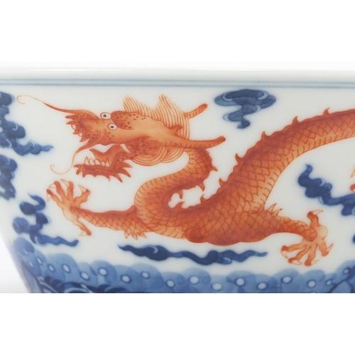 336 - Chinese blue and white porcelain bowl, hand painted in iron red with dragons amongst clouds chasing ... 