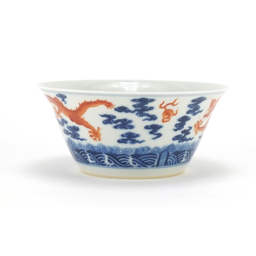 336 - Chinese blue and white porcelain bowl, hand painted in iron red with dragons amongst clouds chasing ... 