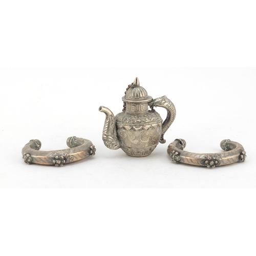 616 - Tibetan Unmarked silver miniature teapot and two silver coloured metal slave bangles, the teapot 7cm... 