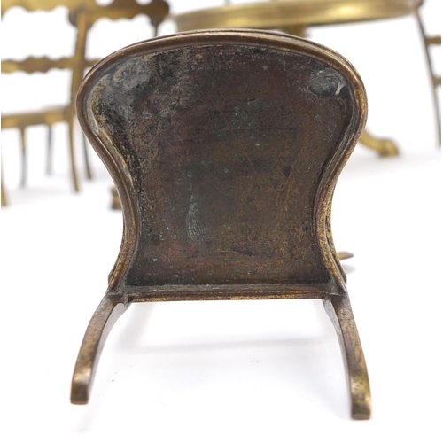 12 - Antique brass dolls house furniture comprising table and six chairs, the table 7.5cm high x 11cm in ... 