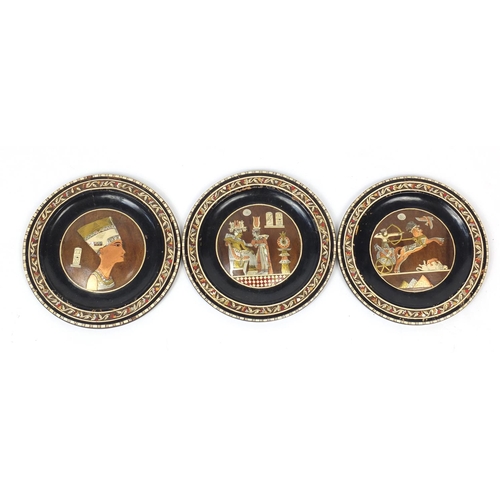 215 - Set of three Egyptian ebonised plates, 25cm diameter