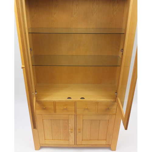 2034 - Light oak illuminated display cabinet with a pair of glazed doors above two drawers and a pair of cu... 