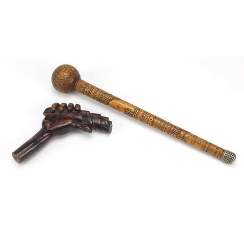 126 - Two carved wood walking stick handles including one carved with a hand clenching a scroll, the large... 