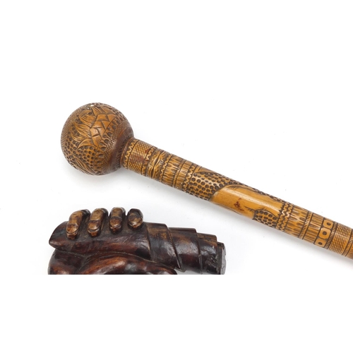 126 - Two carved wood walking stick handles including one carved with a hand clenching a scroll, the large... 