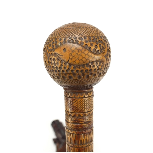 126 - Two carved wood walking stick handles including one carved with a hand clenching a scroll, the large... 