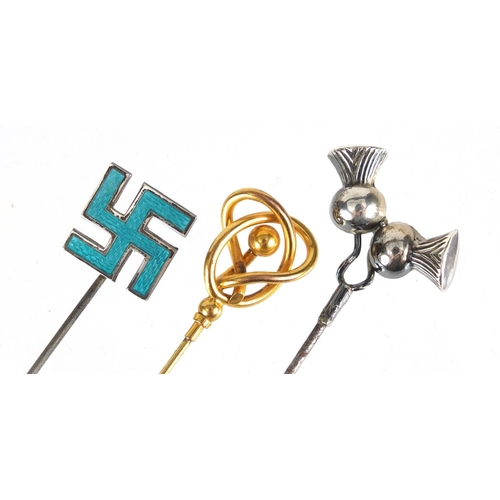 20 - Three hat pins including an unmarked gold and enamel swastika, the largest 25.7cm in length