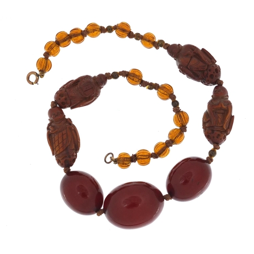 776 - Chinese cherry amber coloured bead and carved coquilla nut necklace, 40cm in length