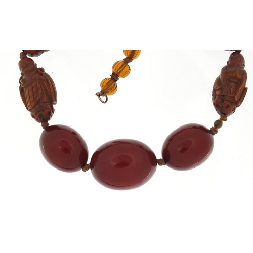 776 - Chinese cherry amber coloured bead and carved coquilla nut necklace, 40cm in length