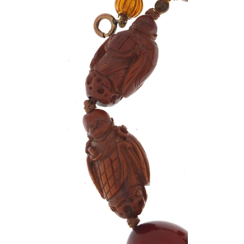 776 - Chinese cherry amber coloured bead and carved coquilla nut necklace, 40cm in length