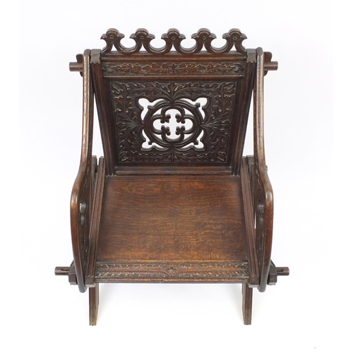 2033 - Gothic style oak hall chair with X-frame support carved with foliage, 88cm high