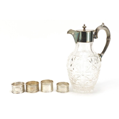 2504 - Four silver napkin rings and a cut glass claret jug with silver plated mounts, the largest 23cm high