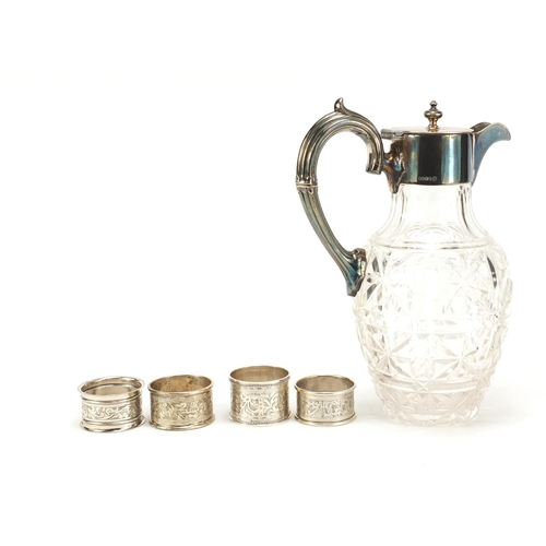 2504 - Four silver napkin rings and a cut glass claret jug with silver plated mounts, the largest 23cm high