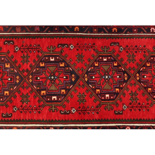 2061 - Rectangular Persian red ground rug having an all over geometric design, 200cm x 101cm