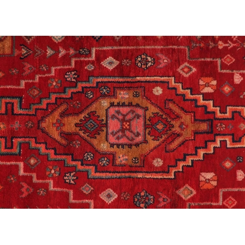 2055 - Rectangular Persian red ground rug having an all over geometric design, 210cm x 126cm