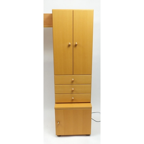 2130 - Beech illuminated wall unit by John Coyle, fitted with a series of cupboard doors, drawers and glass... 