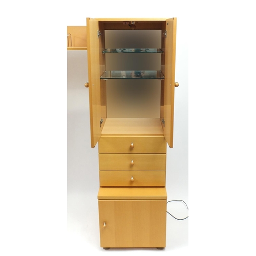 2130 - Beech illuminated wall unit by John Coyle, fitted with a series of cupboard doors, drawers and glass... 