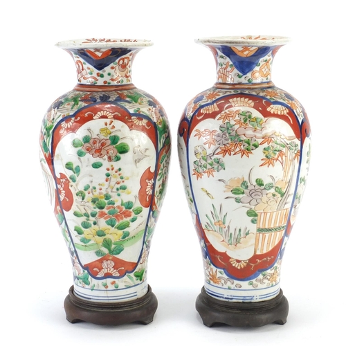 2176 - Pair of Japanese Imari porcelain vases raised on carved hardwood stands, hand painted with flowers, ... 