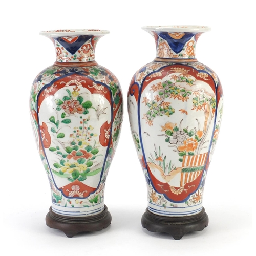 2176 - Pair of Japanese Imari porcelain vases raised on carved hardwood stands, hand painted with flowers, ... 
