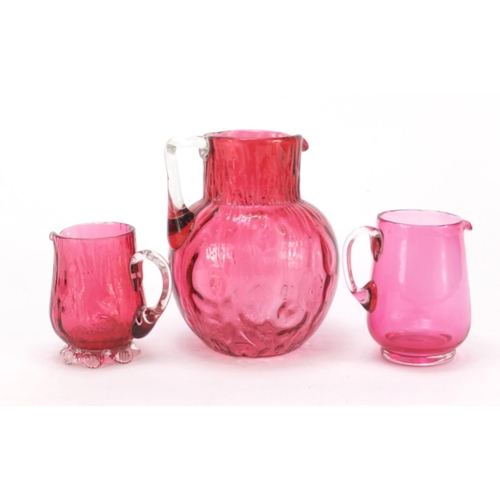 2270 - Three Victorian cranberry glass jugs, the largest 15.5cm high