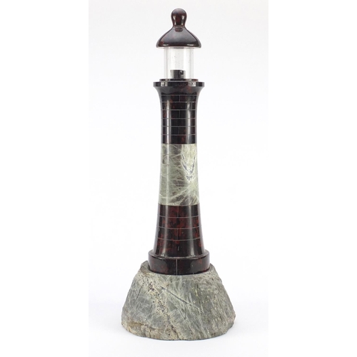 3608 - Large carved red serpentine marble lighthouse design lamp with rocky base, 56cm high