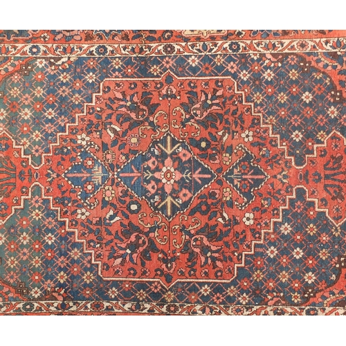 4015 - Rectangular Persian rug having an all over floral design onto a red and blue grounds, 216cm x 147cm