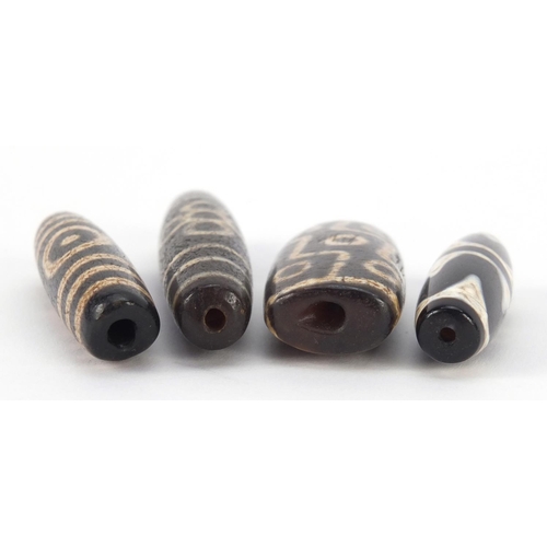 3140 - Four Islamic agate Dzi beads, the largest 8cm wide