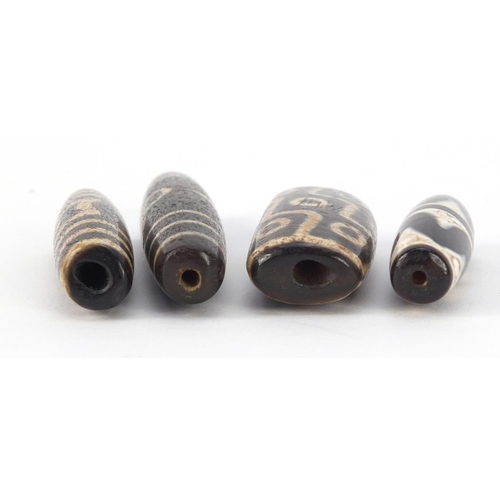 3140 - Four Islamic agate Dzi beads, the largest 8cm wide