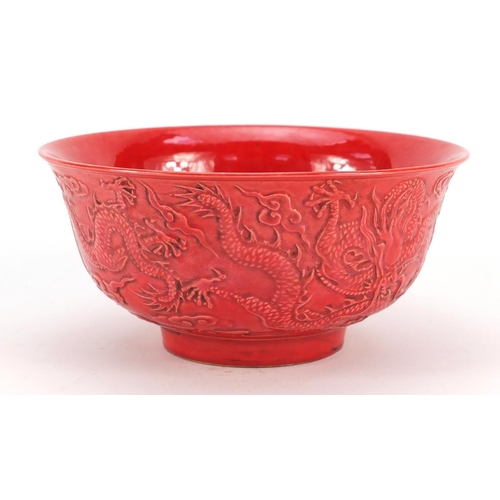 3380 - Chinese red ground porcelain bowl decorated in relief with dragons amongst clouds, six figure charac... 