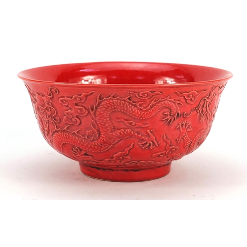 3380 - Chinese red ground porcelain bowl decorated in relief with dragons amongst clouds, six figure charac... 