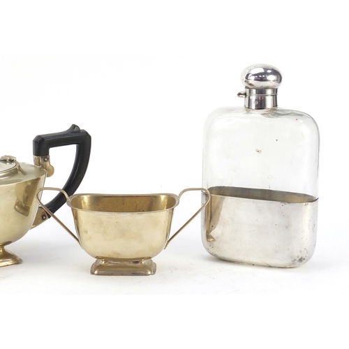 3767 - Silver plate comprising oversized glass hip flask by JDS & Sons and three piece teaset, the largest ... 