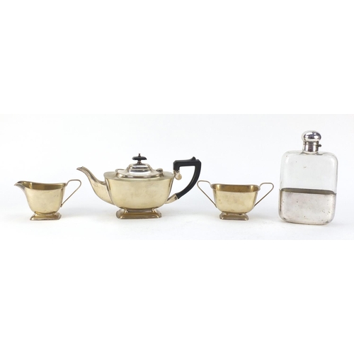 3767 - Silver plate comprising oversized glass hip flask by JDS & Sons and three piece teaset, the largest ... 