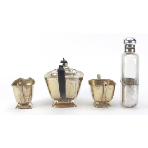 3767 - Silver plate comprising oversized glass hip flask by JDS & Sons and three piece teaset, the largest ... 