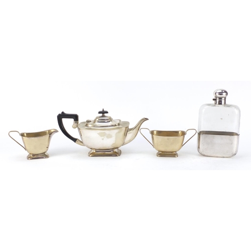 3767 - Silver plate comprising oversized glass hip flask by JDS & Sons and three piece teaset, the largest ... 