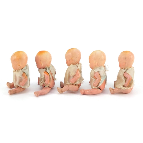 3310 - Five hand painted bisque porcelain dolls with articulated limbs, housed in a basket, each 7.5cm high