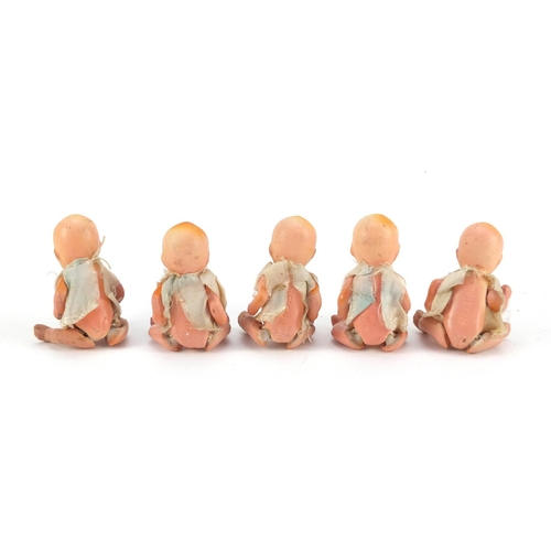 3310 - Five hand painted bisque porcelain dolls with articulated limbs, housed in a basket, each 7.5cm high